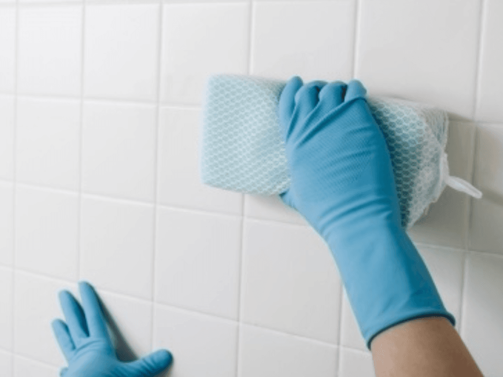 Cleaning ceramic tiles with a sponge for spotless kitchen, bathroom, or patio surfaces.