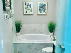 Modern bathroom remodel featuring a marble bathtub, minimalist decor, and greenery for a spa-like atmosphere.